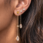 Close-up of an ear wearing a set of gold earrings with gemstones.